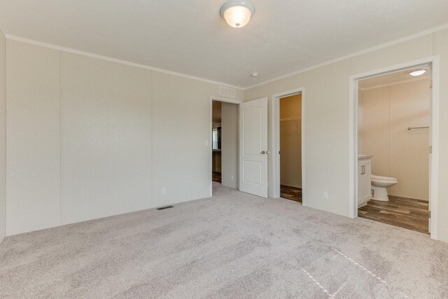 575 Gallery Dr Unit 48, Eaton Rapids, MI 48827 - unfurnished bedroom with carpet floors, crown molding, a walk in closet, connected bathroom, and a closet