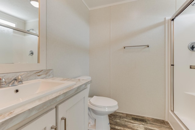 575 Gallery Dr Unit 48, Eaton Rapids, MI 48827 - full bathroom featuring crown molding, a shower with door, vanity, wood finished floors, and toilet