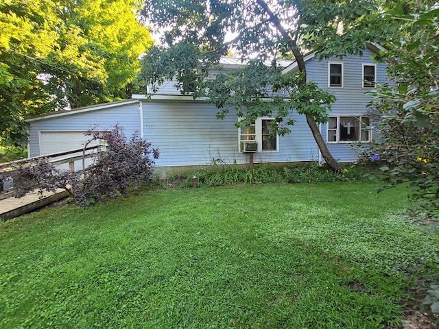 back of property featuring a lawn, cooling unit, and a garage