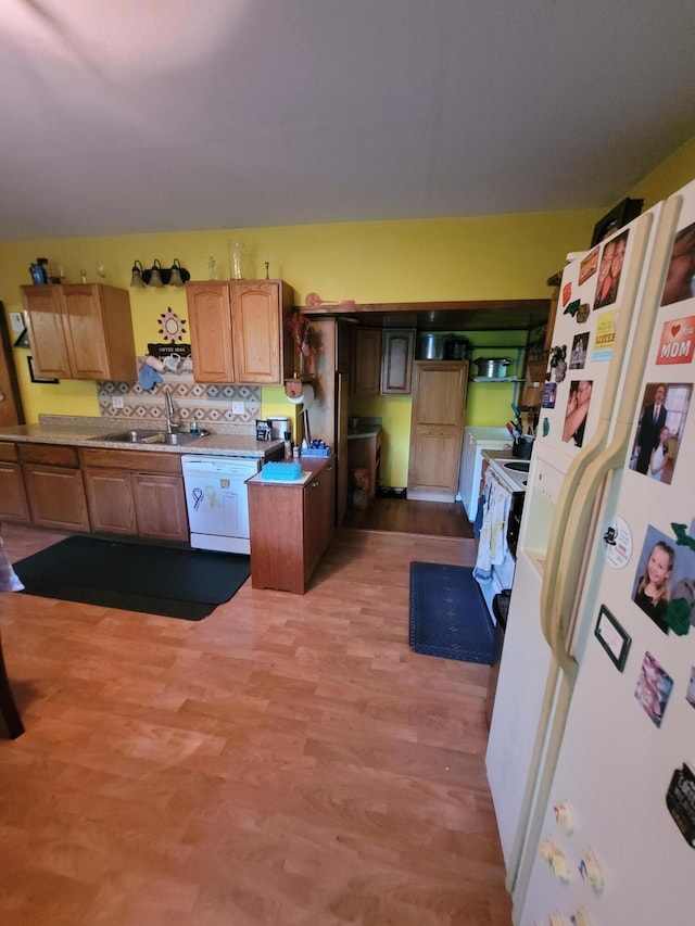 kitchen with a center island, white appliances, backsplash, sink, and light wood-type flooring