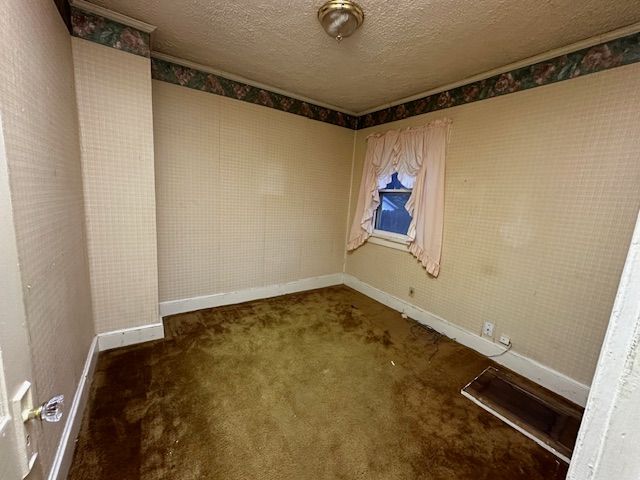 unfurnished room featuring dark colored carpet and a textured ceiling