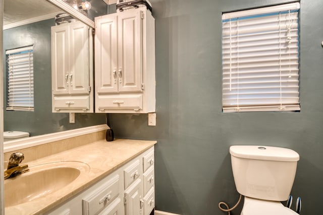 bathroom featuring toilet, vanity, and ornamental molding