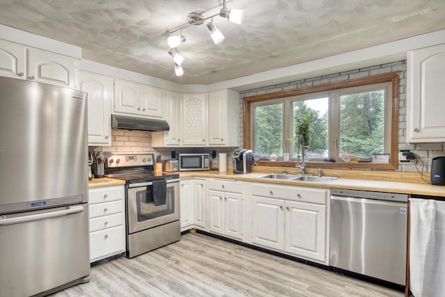 kitchen with white cabinets, appliances with stainless steel finishes, light wood-type flooring, and sink