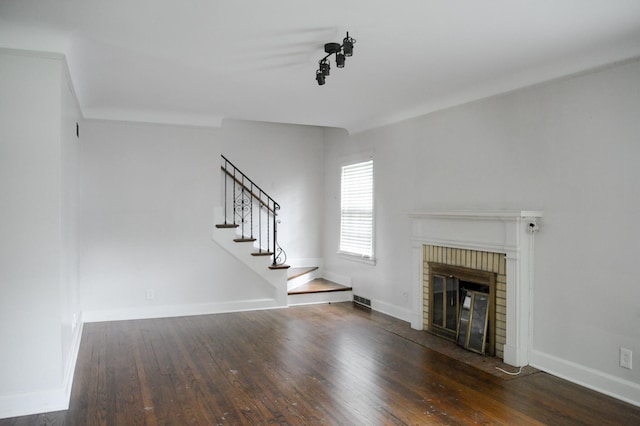 unfurnished living room featuring dark hardwood / wood-style floors and a brick fireplace