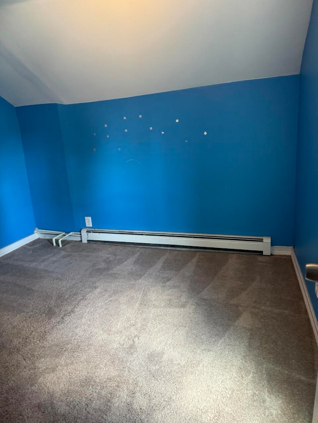 carpeted spare room featuring vaulted ceiling and a baseboard heating unit