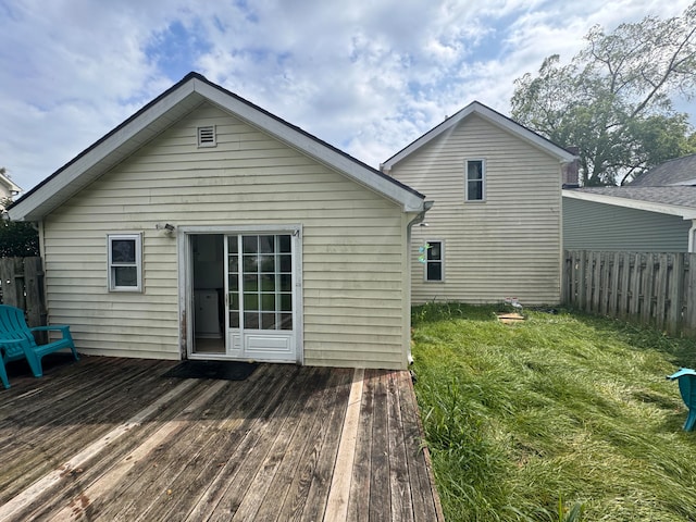 back of property featuring a deck and a lawn