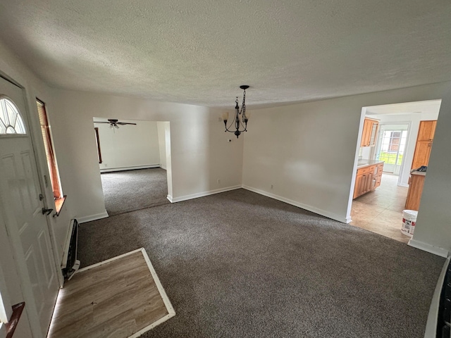 interior space with ceiling fan with notable chandelier, light colored carpet, baseboard heating, and a textured ceiling