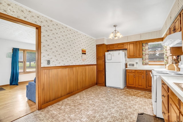 kitchen with pendant lighting, white appliances, crown molding, light hardwood / wood-style flooring, and a chandelier