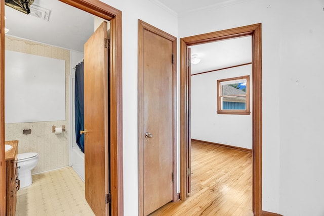 hallway featuring light hardwood / wood-style flooring and crown molding