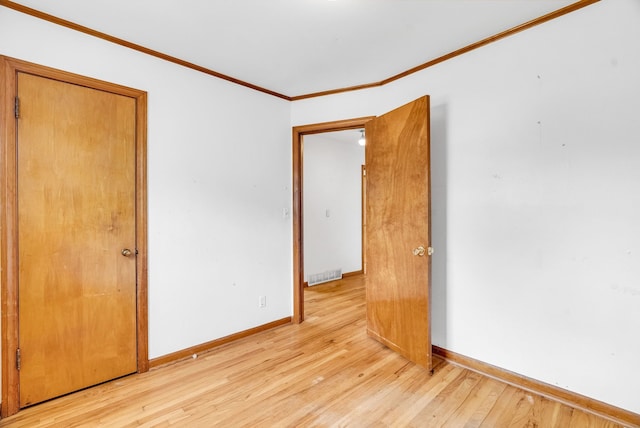 empty room with crown molding and light hardwood / wood-style flooring