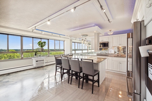 kitchen featuring a breakfast bar, white cabinets, a textured ceiling, stone countertops, and a kitchen island