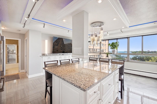 kitchen with white cabinetry, a breakfast bar, light stone counters, and a textured ceiling