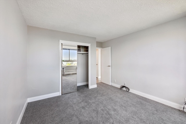 unfurnished bedroom featuring a closet, dark colored carpet, a textured ceiling, and a baseboard heating unit