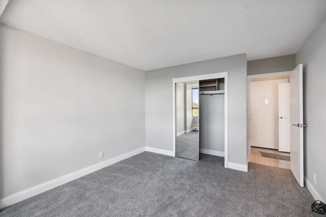 unfurnished bedroom featuring dark colored carpet, a textured ceiling, a baseboard radiator, and a closet