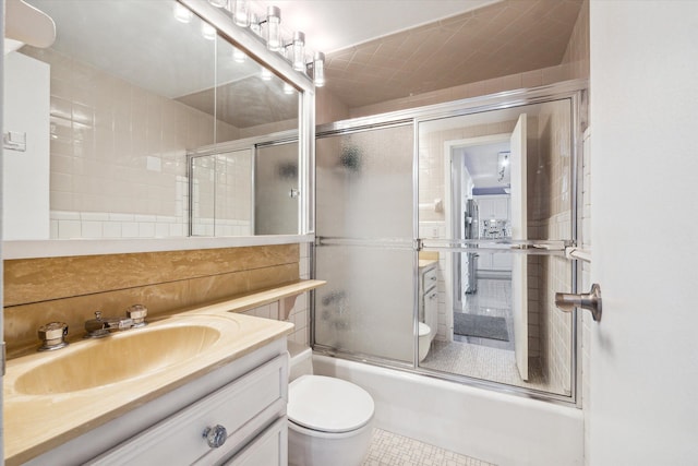 full bathroom with combined bath / shower with glass door, vanity, toilet, and tile patterned flooring