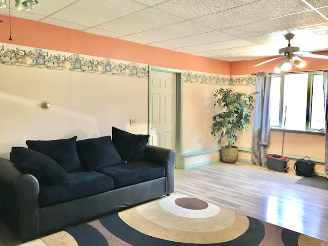 living room featuring hardwood / wood-style flooring, a drop ceiling, and ceiling fan