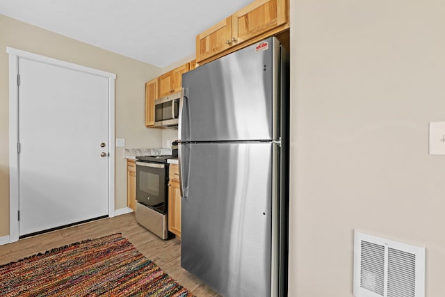 kitchen featuring light brown cabinets, appliances with stainless steel finishes, and light hardwood / wood-style flooring