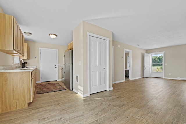 kitchen with light hardwood / wood-style floors, light brown cabinetry, sink, and stainless steel refrigerator