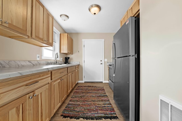 kitchen with sink, dark wood-type flooring, light brown cabinets, and appliances with stainless steel finishes