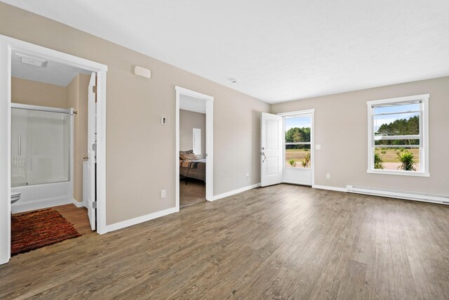 2835 Walton Rd, Kingsley, MI 49649 - unfurnished living room featuring a baseboard radiator, wood finished floors, and baseboards
