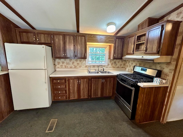 kitchen with dark carpet, white refrigerator, sink, a textured ceiling, and stainless steel range with gas stovetop