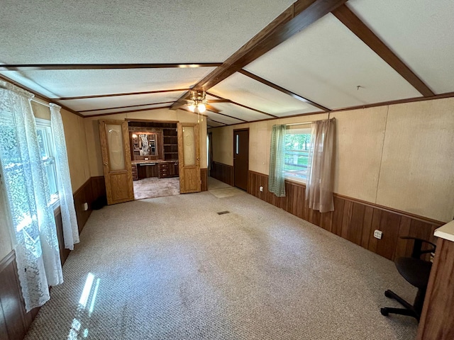 unfurnished living room featuring vaulted ceiling with beams, ceiling fan, a textured ceiling, and light carpet