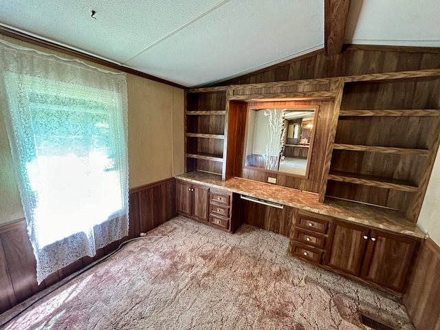 unfurnished office with a textured ceiling, wood walls, built in desk, and a healthy amount of sunlight