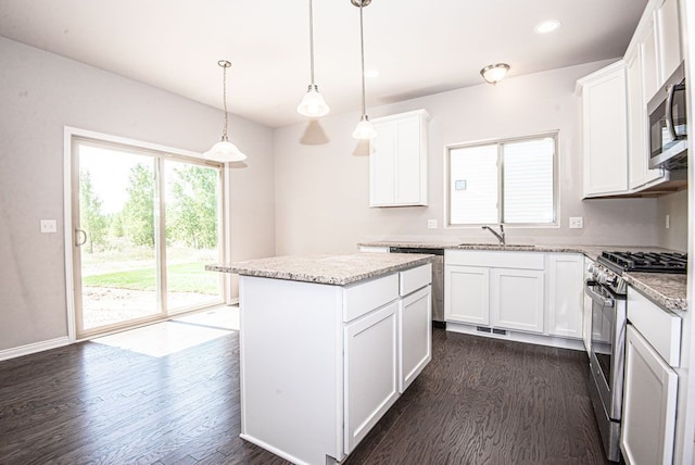 kitchen featuring appliances with stainless steel finishes, dark hardwood / wood-style flooring, a center island, white cabinetry, and hanging light fixtures