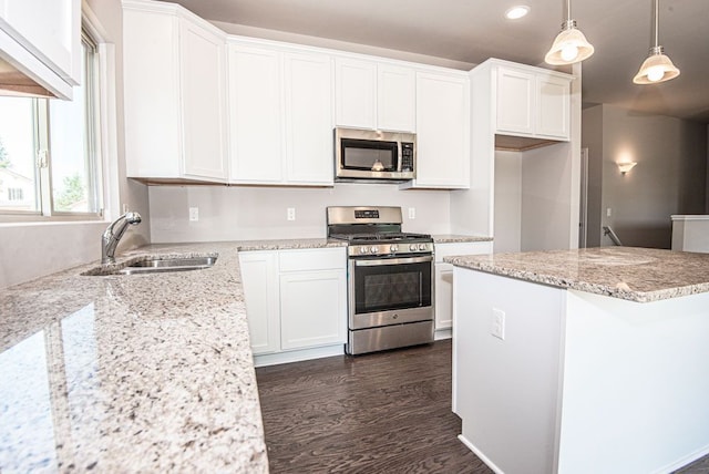 kitchen with white cabinetry, sink, hanging light fixtures, stainless steel appliances, and dark hardwood / wood-style floors