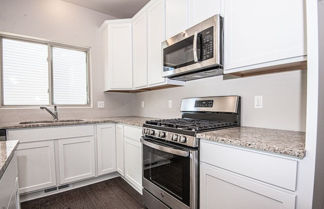 kitchen featuring white cabinetry, dark hardwood / wood-style flooring, light stone counters, and appliances with stainless steel finishes