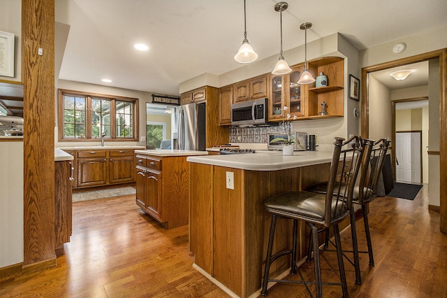 5925 Jagger Rd, Ludington, MI 49431 - kitchen featuring appliances with stainless steel finishes, brown cabinetry, wood finished floors, light countertops, and recessed lighting
