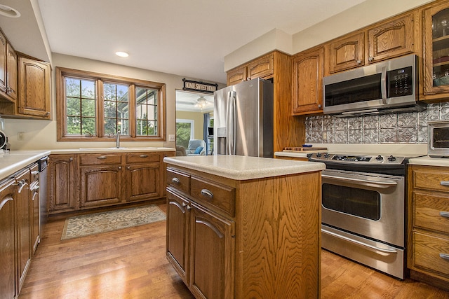 5925 Jagger Rd, Ludington, MI 49431 - kitchen with appliances with stainless steel finishes, brown cabinetry, a kitchen island, light wood-style floors, and recessed lighting