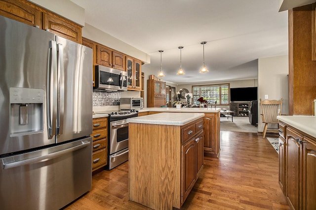 5925 Jagger Rd, Ludington, MI 49431 - kitchen featuring stainless steel appliances, brown cabinetry, a kitchen island, glass insert cabinets, and light countertops