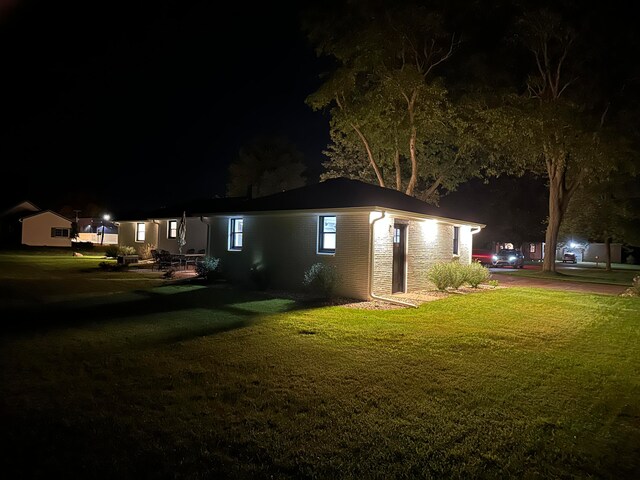 property exterior at night featuring a lawn