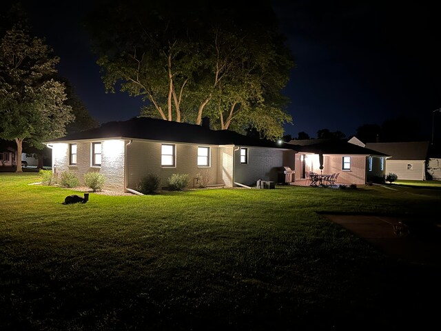 back house at night with a yard and a patio