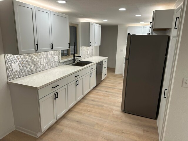 kitchen featuring backsplash, white cabinets, sink, appliances with stainless steel finishes, and light hardwood / wood-style floors