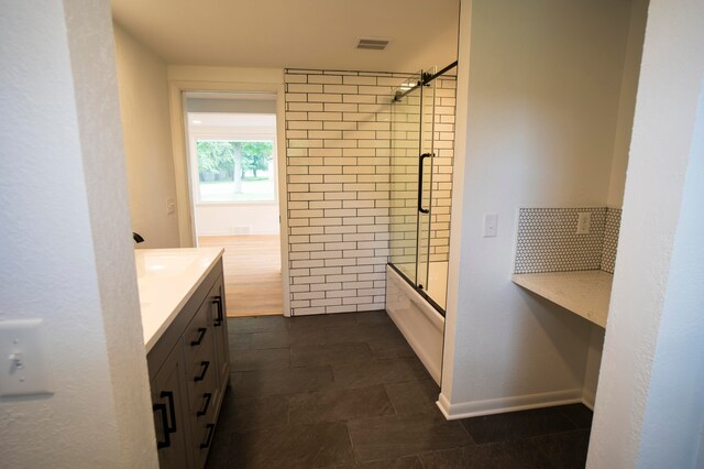 bathroom featuring tile patterned flooring, vanity, and shower / bath combination with glass door