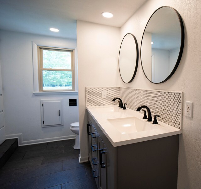 bathroom featuring vanity, toilet, and backsplash