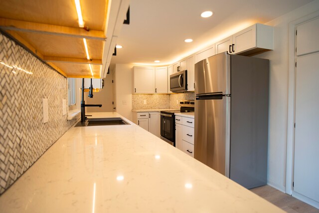 kitchen with light wood-type flooring, white cabinetry, sink, and appliances with stainless steel finishes