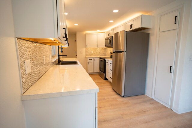 kitchen featuring sink, decorative backsplash, light hardwood / wood-style floors, white cabinetry, and stainless steel appliances