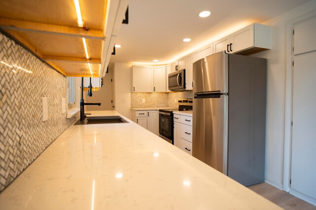 kitchen featuring sink, white cabinets, stainless steel appliances, and light hardwood / wood-style floors