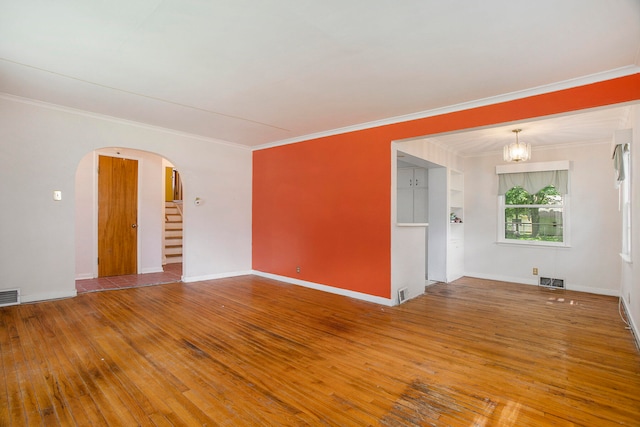 empty room with a chandelier, hardwood / wood-style flooring, and ornamental molding