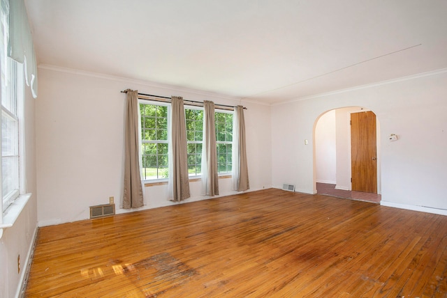 empty room with hardwood / wood-style floors and crown molding