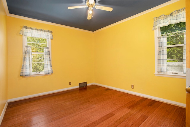 empty room with crown molding, plenty of natural light, and wood-type flooring