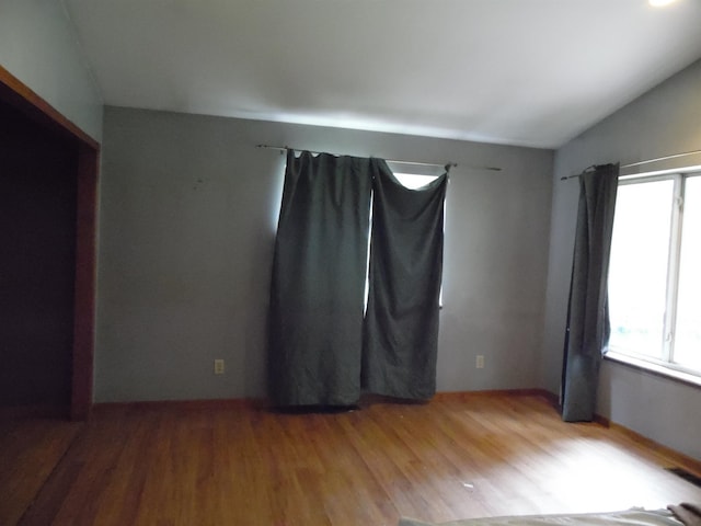 unfurnished room featuring vaulted ceiling and light hardwood / wood-style flooring