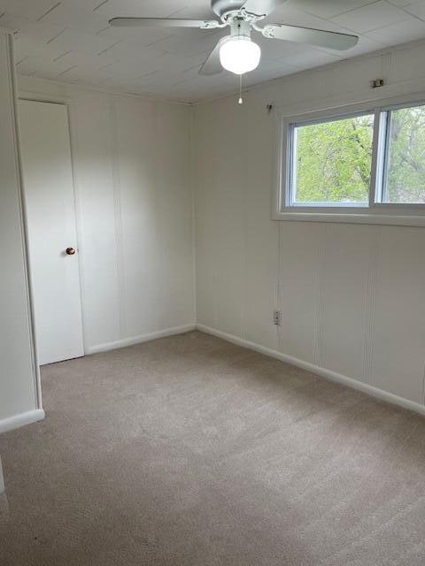 carpeted spare room featuring ceiling fan