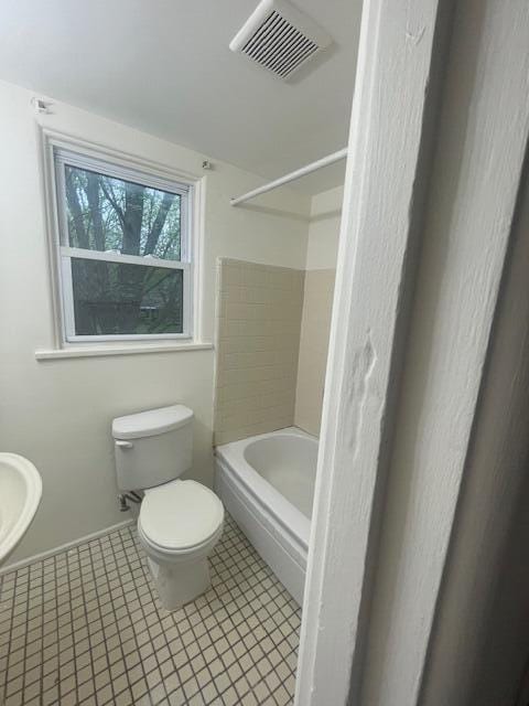 bathroom featuring toilet, tile patterned floors, and shower / washtub combination