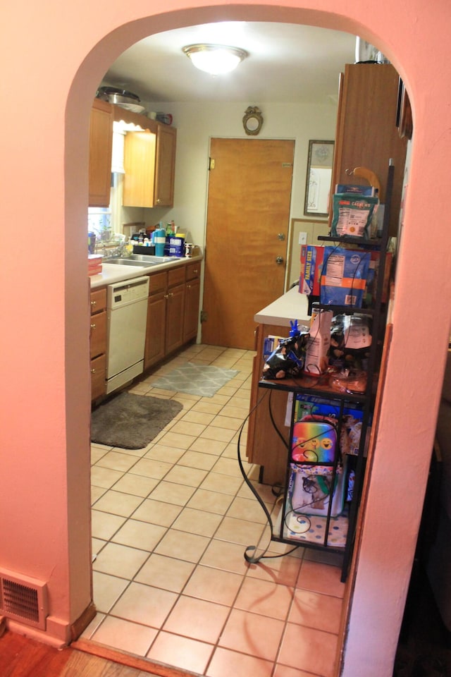 kitchen featuring sink, white dishwasher, and light tile patterned flooring