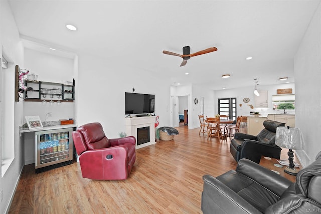 living room with wine cooler, ceiling fan, light hardwood / wood-style flooring, and wet bar