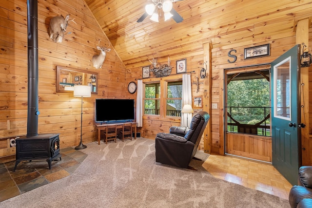 living room featuring a wood stove, high vaulted ceiling, wood ceiling, and wood walls